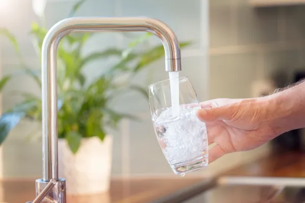 Wasser aus dem Hahn fließt in ein Glas